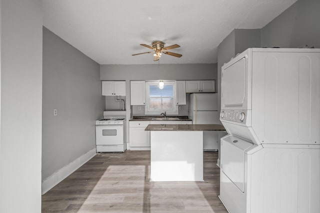 kitchen featuring sink, white appliances, ceiling fan, stacked washing maching and dryer, and light hardwood / wood-style floors