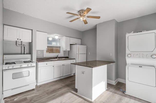 kitchen with white cabinetry, sink, stacked washer and dryer, a center island, and white appliances