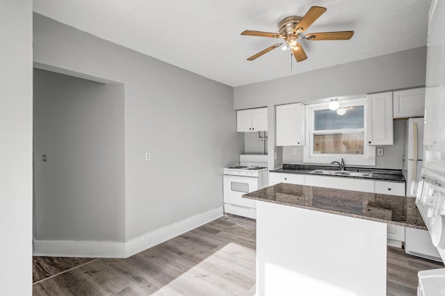 kitchen with sink, white appliances, dark stone counters, light hardwood / wood-style floors, and white cabinets