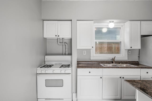 kitchen featuring white cabinetry, sink, white range with gas stovetop, and dark stone countertops