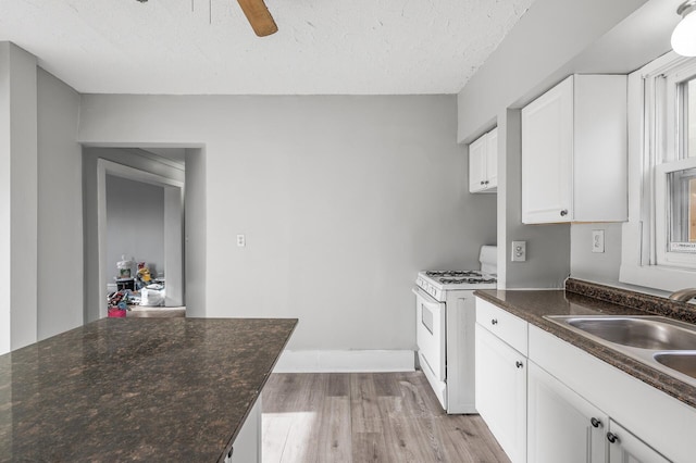 kitchen featuring sink, light wood-type flooring, white cabinets, white range with gas cooktop, and a textured ceiling