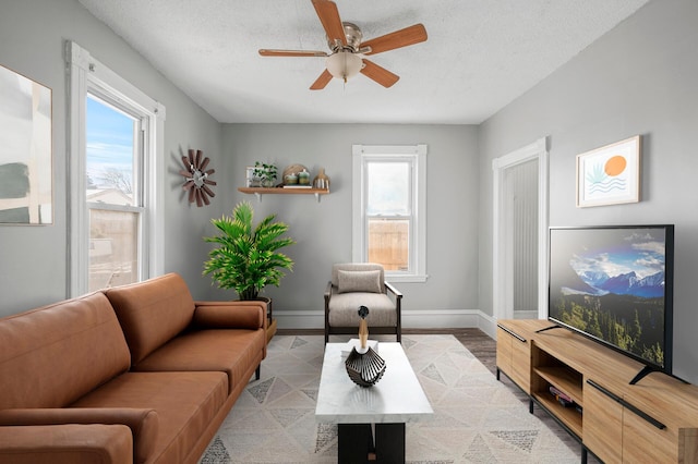 living room featuring ceiling fan, a textured ceiling, and light wood-type flooring