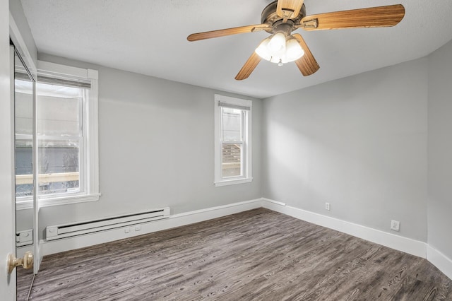 unfurnished room featuring ceiling fan, dark hardwood / wood-style flooring, and a baseboard heating unit