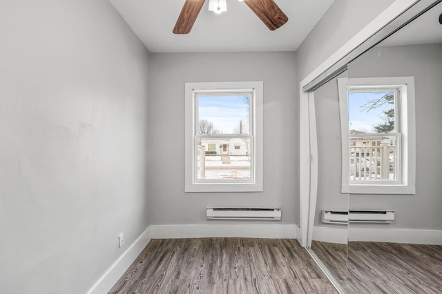 doorway with wood-type flooring, a baseboard radiator, and a healthy amount of sunlight