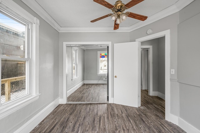 unfurnished bedroom with multiple windows, dark wood-type flooring, a closet, and ceiling fan