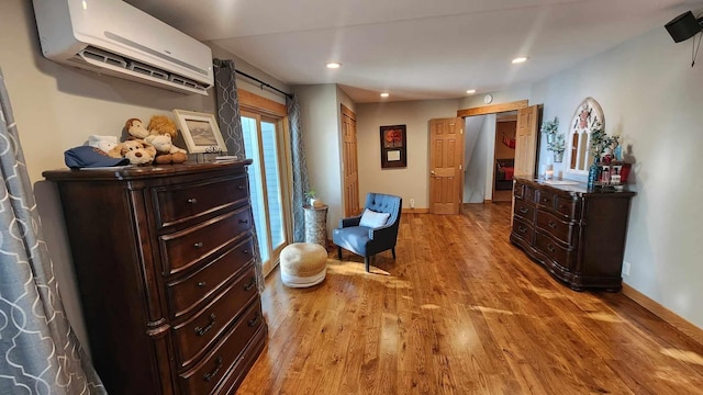 sitting room featuring an AC wall unit, light wood-type flooring, and a barn door