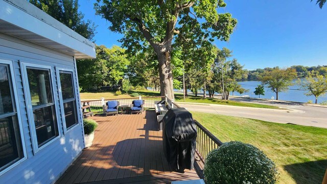 wooden deck featuring grilling area, a water view, and a yard