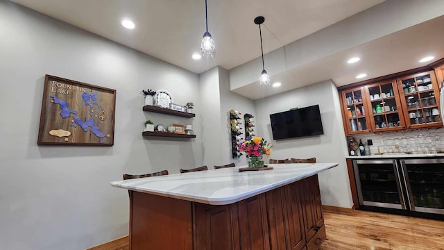 interior space featuring pendant lighting, light hardwood / wood-style flooring, a breakfast bar, light stone countertops, and decorative backsplash