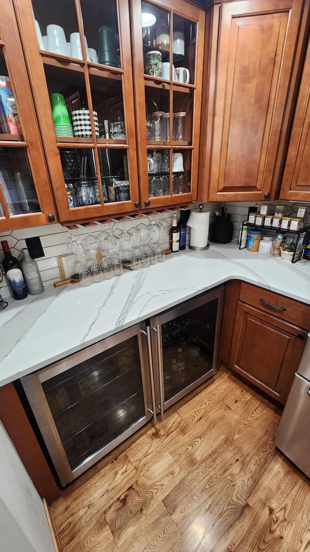 kitchen with light stone counters, beverage cooler, light hardwood / wood-style flooring, and decorative backsplash