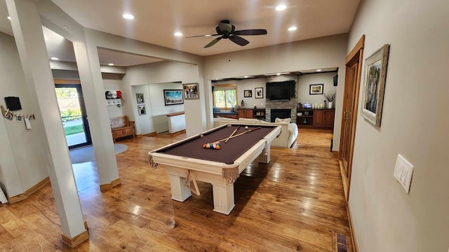 game room featuring ceiling fan, a stone fireplace, hardwood / wood-style flooring, and billiards