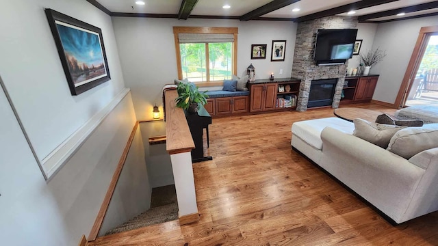 living room with light hardwood / wood-style flooring, beam ceiling, a fireplace, and a healthy amount of sunlight