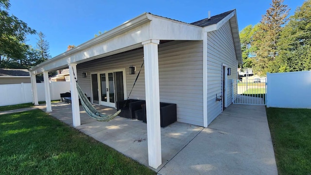 rear view of house with a lawn, french doors, and a patio area