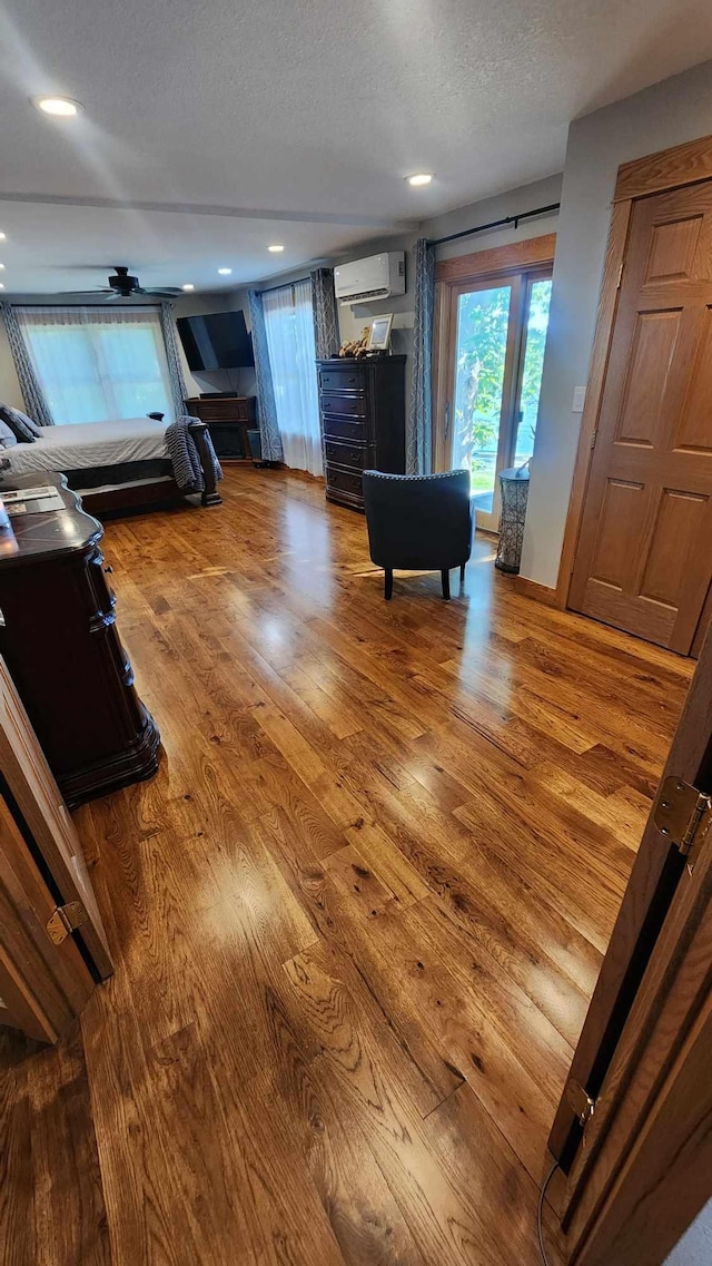 interior space featuring an AC wall unit, a textured ceiling, and hardwood / wood-style flooring