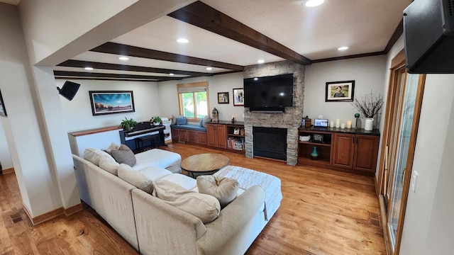 living room featuring light hardwood / wood-style floors, a stone fireplace, and beam ceiling