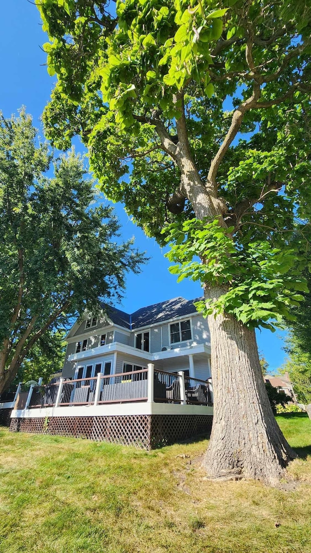 back of property featuring a lawn and a wooden deck