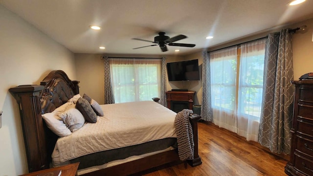 bedroom featuring multiple windows, hardwood / wood-style flooring, and ceiling fan