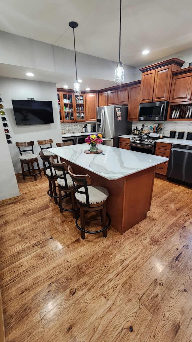 kitchen with a kitchen island, light hardwood / wood-style flooring, stainless steel appliances, and tasteful backsplash