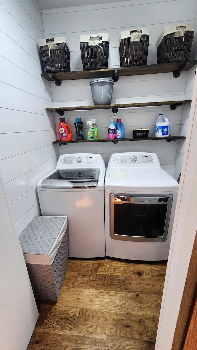 washroom featuring dark wood-type flooring, wood walls, and washer and dryer