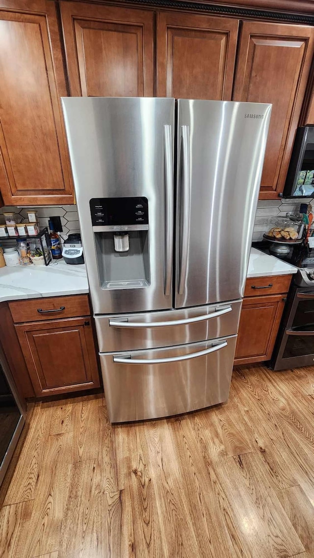 details with light hardwood / wood-style flooring, stainless steel appliances, and backsplash