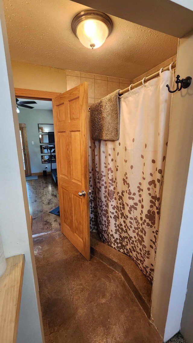 bathroom featuring a textured ceiling, concrete flooring, and a shower with curtain