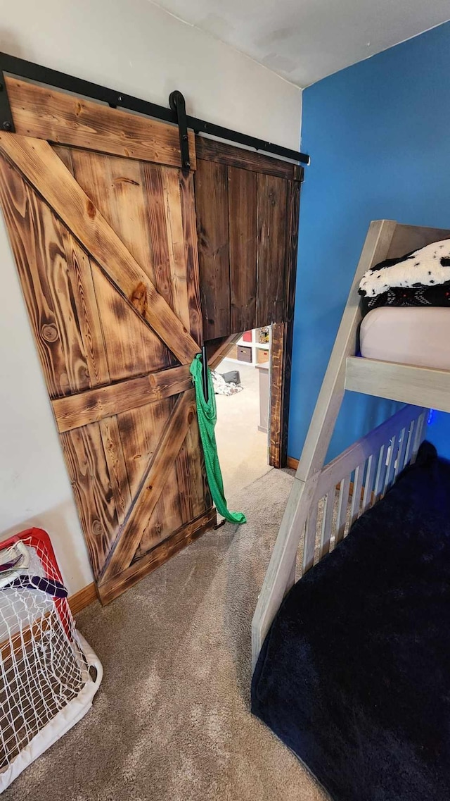 bedroom with a barn door and carpet