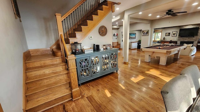 interior space with pool table, a stone fireplace, ceiling fan, and hardwood / wood-style flooring