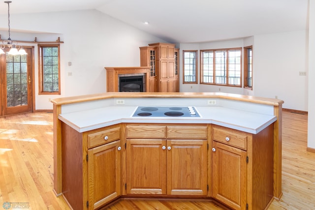 kitchen with light wood-type flooring, a healthy amount of sunlight, lofted ceiling, and decorative light fixtures