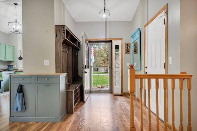 mudroom with light hardwood / wood-style floors, lofted ceiling, and an inviting chandelier