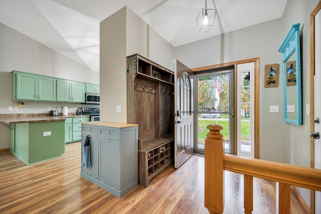 kitchen featuring lofted ceiling, hanging light fixtures, green cabinetry, appliances with stainless steel finishes, and light hardwood / wood-style floors