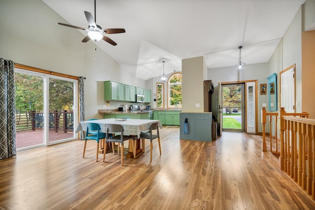 dining area with ceiling fan, plenty of natural light, high vaulted ceiling, and light wood-type flooring