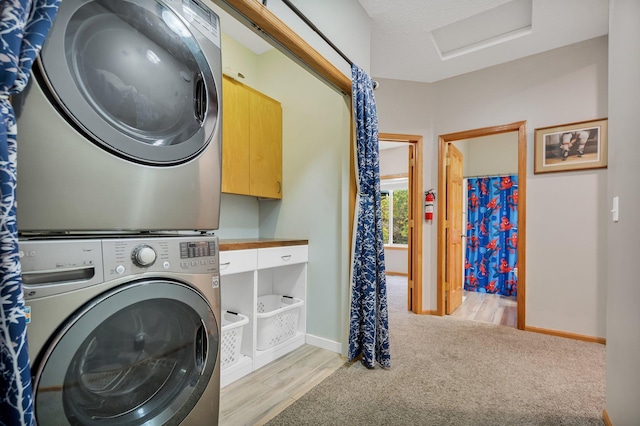 washroom featuring a textured ceiling, stacked washing maching and dryer, and light hardwood / wood-style floors