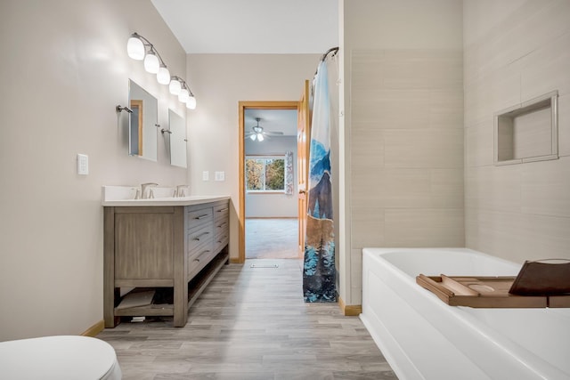 bathroom with vanity, ceiling fan, a bath, hardwood / wood-style flooring, and toilet