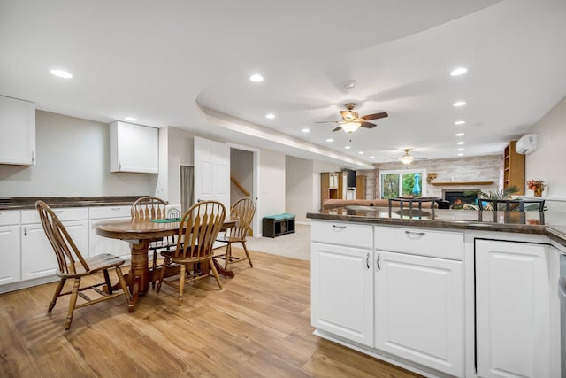 kitchen with a wall mounted AC, light wood-type flooring, white cabinetry, and ceiling fan