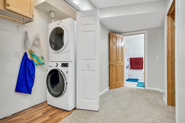 laundry room featuring stacked washer / dryer and light hardwood / wood-style flooring