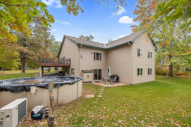 back of house featuring a lawn, a pool side deck, and a patio