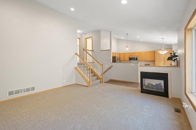 unfurnished living room featuring light colored carpet, a fireplace, and vaulted ceiling