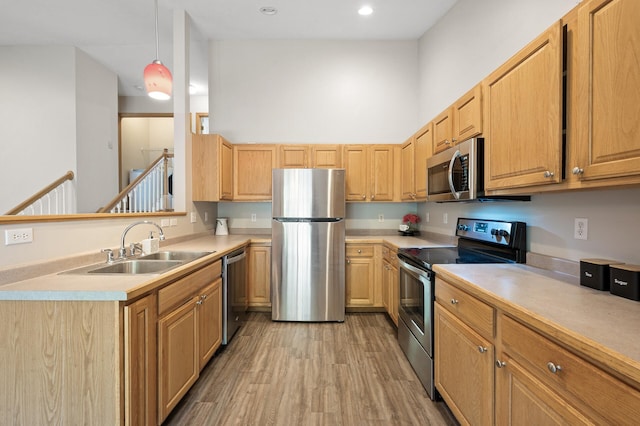 kitchen with pendant lighting, light hardwood / wood-style floors, sink, stainless steel appliances, and light brown cabinets