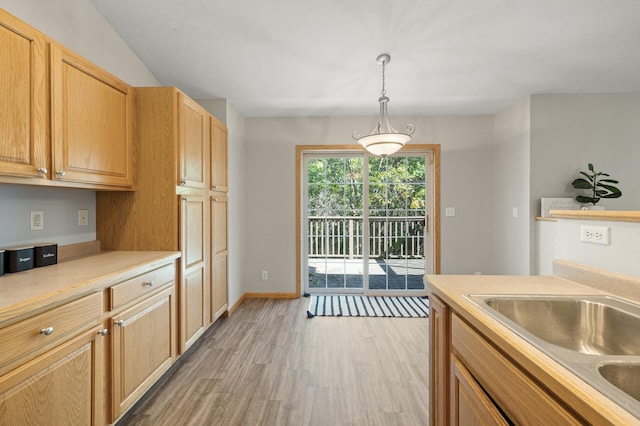 kitchen featuring light brown cabinets, light wood-type flooring, hanging light fixtures, and sink