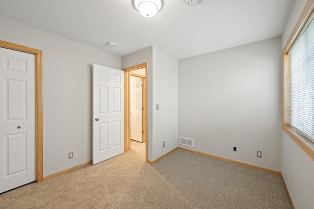 unfurnished bedroom with light carpet and a closet