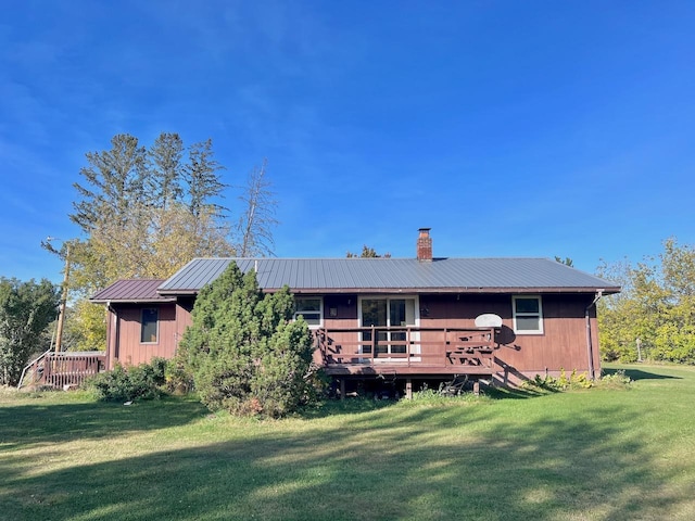 rear view of property featuring a deck and a lawn