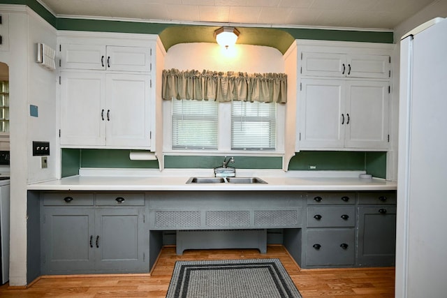 kitchen with ornamental molding, light wood-type flooring, sink, and white cabinets