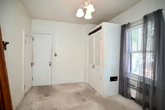 interior space featuring light carpet, a chandelier, and a textured ceiling