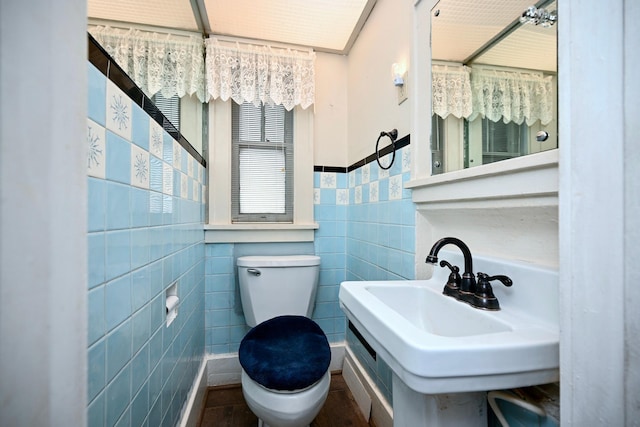 bathroom with sink, tile walls, and toilet