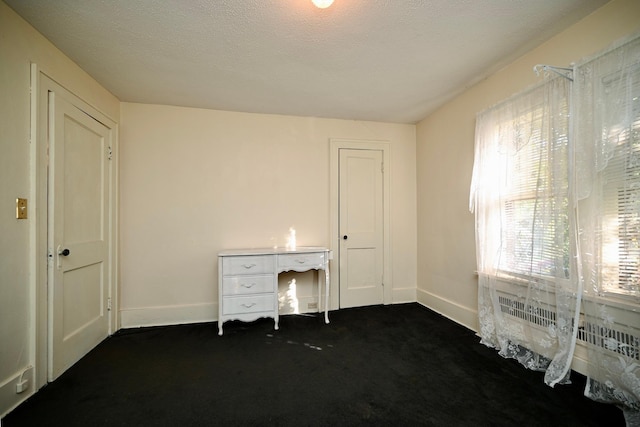 unfurnished office featuring dark carpet and a textured ceiling