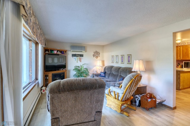 living room with a textured ceiling, light wood-type flooring, a baseboard heating unit, and an AC wall unit