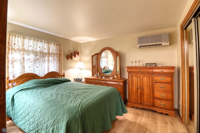 bedroom featuring a wall mounted AC and light hardwood / wood-style flooring