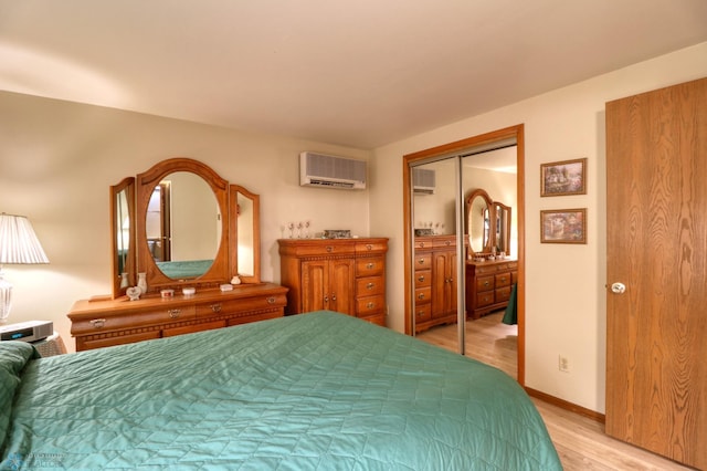 bedroom with light wood-type flooring, a closet, and a wall mounted AC