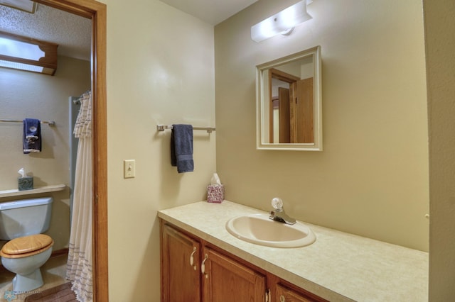 bathroom with a textured ceiling, vanity, and toilet