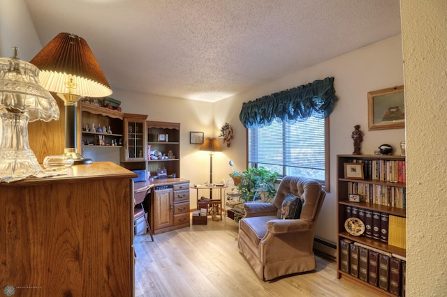 living area with a textured ceiling, baseboard heating, and light hardwood / wood-style floors