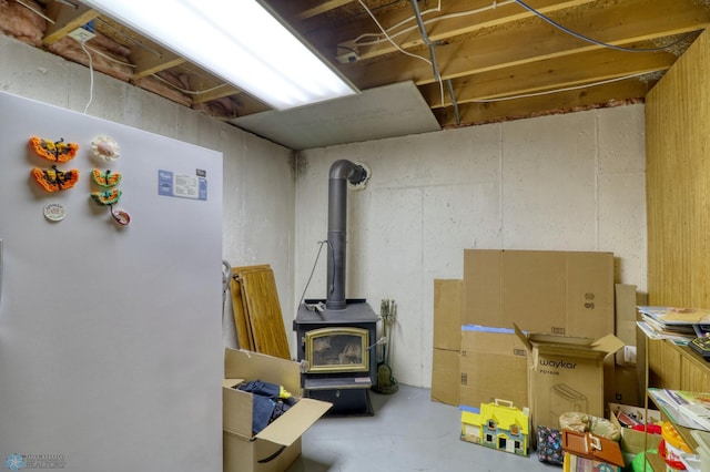 basement featuring a wood stove and white fridge